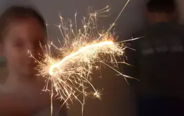 Uczennica trzymająca w ręku zimne ognie.