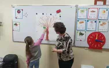 1 uczennica przywiesza listek ze swoim imieniem na klasowym drzewie genealogicznym