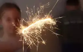 Uczennica trzymająca w ręku zimne ognie.