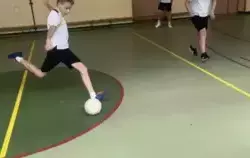 trzech uczniów gra w piłkę nożną, jeden kopie piłkę