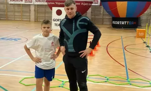 Uczeń Jan Stępień pozuje w sali gimnastycznej z nauczycielem wychowania fizycznego Sebastianem Ostrowskim 