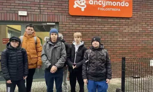 Uczniowie 8b stoją przed budynkiem, na ścianie szyld "Ancymondo" 