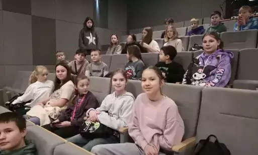 Uczniowie siedzący w kinowych fotelach. 