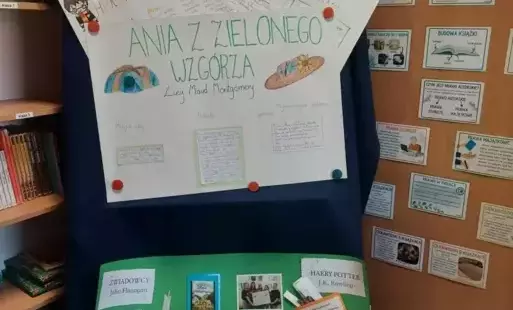 Na tle niebieskiego materiału wiszą wykonane przez uczniów plakaty. 
