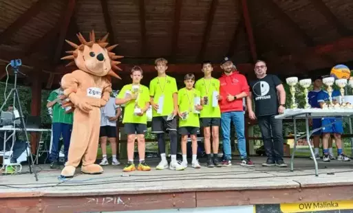 drużyna 4 chłopców w żółtych strojach pozuje na scenie w parku miejskim z medalami i dyplomami