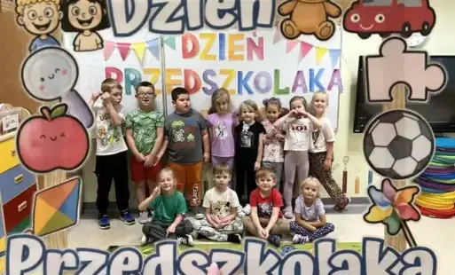 Przedszkolaki na tle tablicy, napis "dzień przedszkolaka" 