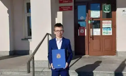 Uczeń stoi przed urzędem miasta Zgierza 