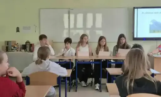 uczniowie klasy siódmej siedzą przed młodszymi 