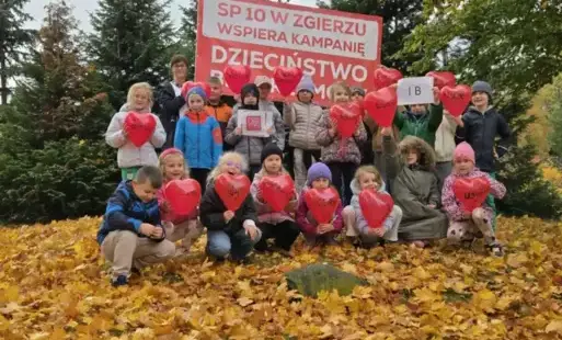 uczniowie pozują z banerem i balonami-serduszkami 