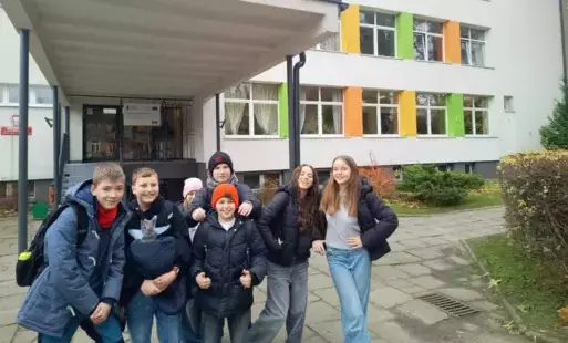 Kilkoro uczniów z klasy 6 a i b stoi na tle budynku SP6