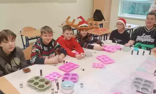 grupa chłopców z 6a siedzi przy stoliku, przed nimi foremki na mydełka 