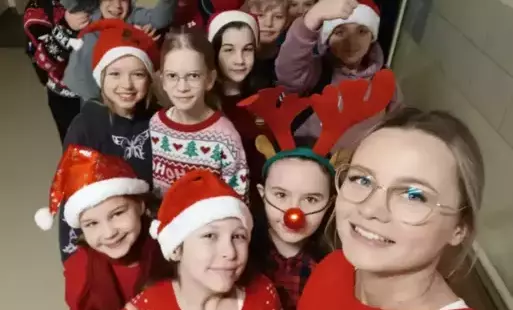Twarze uczniów klasy 4B w czapkach mikołajów oraz świątecznych swetrach. 